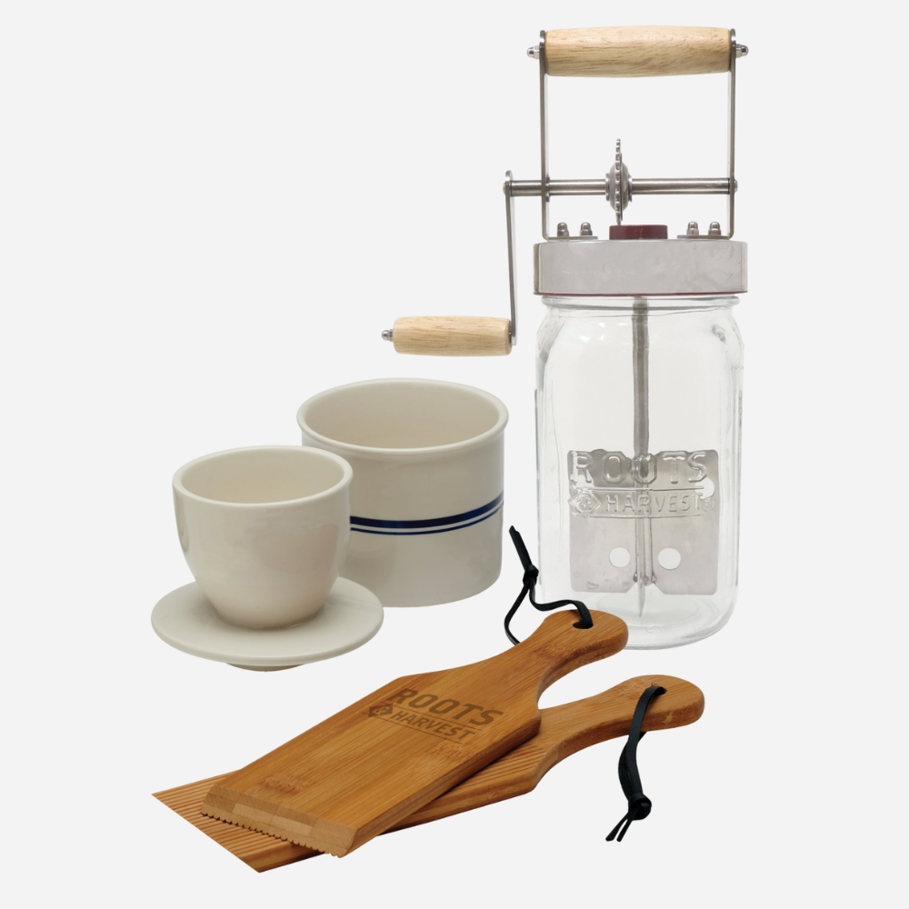 Mason jar coffee press with ceramic cups and wooden tools on a white background