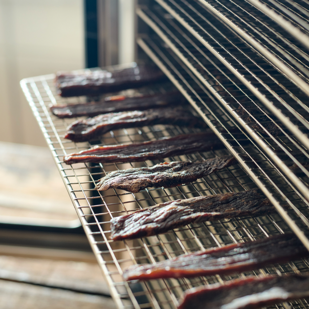 Dried meat strips on a cooling rack with a blurred background