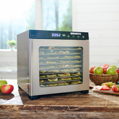 Food dehydrator with dried fruits and vegetables on a wooden table.