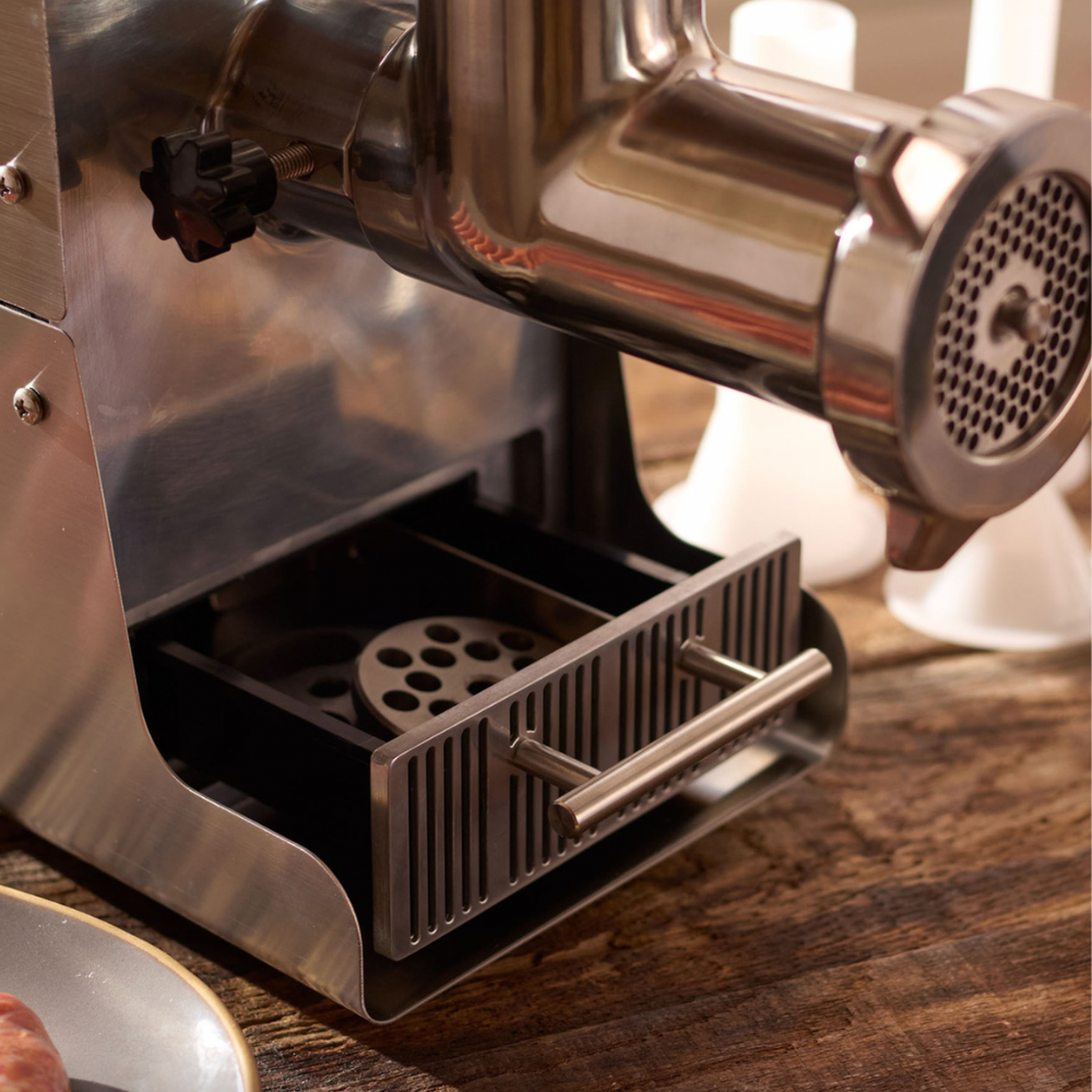 Close-up of a metal meat grinder on a wooden surface