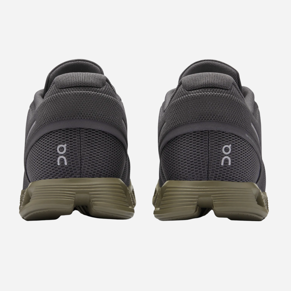 Pair of gray running shoes with green sole on a white background