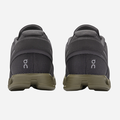 Pair of gray running shoes with green sole on a white background